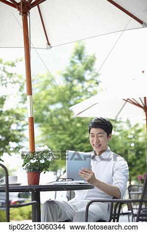 Picture - a man with a white shirt working with a tablet. Fotosearch