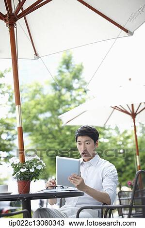 Stock Image - a man with a white shirt working with a tablet. Fotosearch