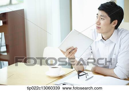Stock Photo - a man with a white shirt working with a tablet. Fotosearch