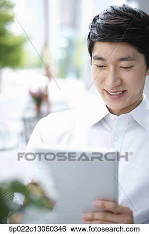 a man with a white shirt working with a tablet View Large Photo Image Stock Photograph - a man with a white shirt working with a tablet. Fotosearch