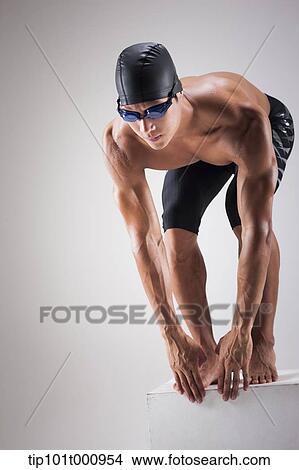 Picture - a man with swimming goggle and hat In swimming pose. Fotosearch