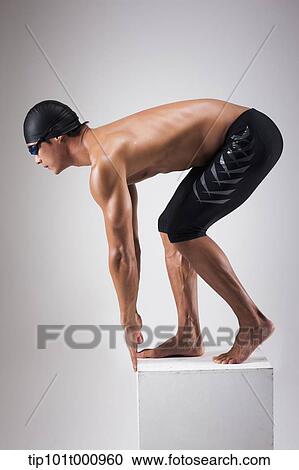 Stock Image - a man with swimming goggle and hat In swimming pose. Fotosearch