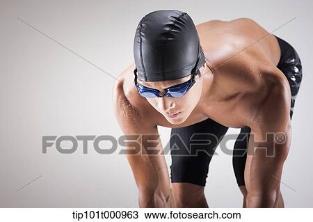 Stock Image - a man with swimming goggle and hat In swimming pose. Fotosearch