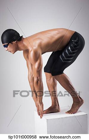 Stock Photo - a man with swimming goggle and hat In swimming pose. Fotosearch