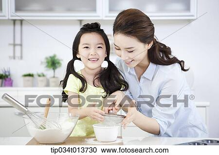 Stock Image - a mother and a daughter cooking together. Fotosearch