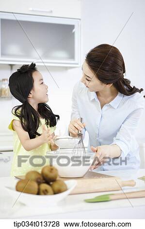 Stock Photo - a mother and a daughter cooking together. Fotosearch