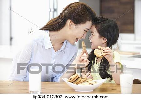 a mother and a daughter enjoying cookies in the kitchen View Large Photo Image Stock Image - a mother and a daughter enjoying cookies in the kitchen. Fotosearch