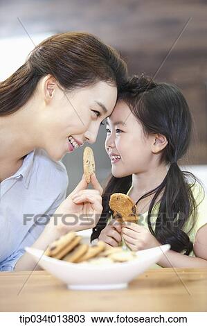 a mother and a daughter enjoying cookies in the kitchen View Large Photo Image Stock Image - a mother and a daughter enjoying cookies in the kitchen. Fotosearch