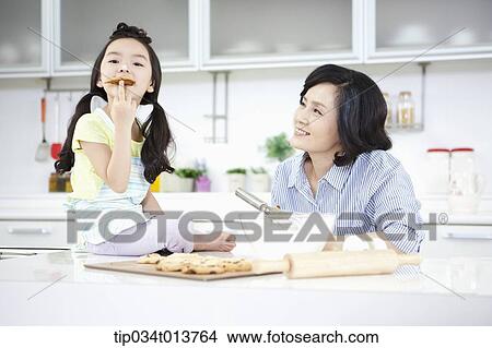 Picture - a mother and a daughter in the kitchen. Fotosearch