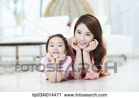 Stock Image - a mother and daughter lying on the floor together. Fotosearch
