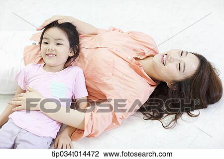 Stock Image - a mother and daughter lying on the floor together. Fotosearch