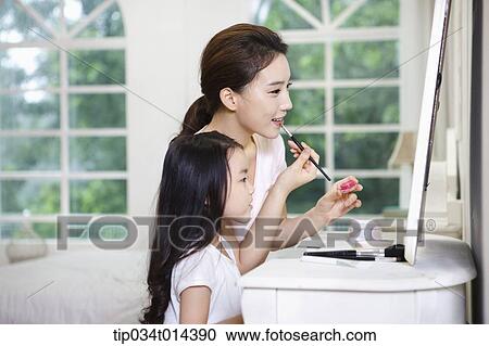 Stock Image - a mother and daughter on make up table. Fotosearch