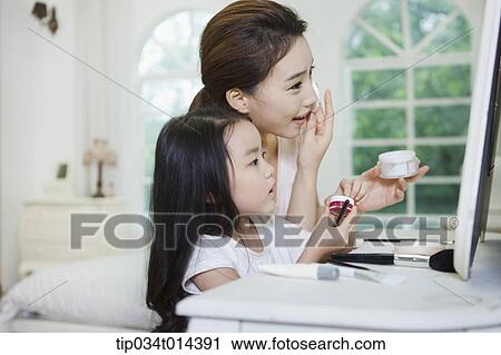 Stock Image - a mother and daughter on make up table. Fotosearch