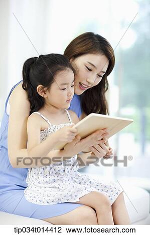 Stock Image - a mother and daughter reading a book together. Fotosearch