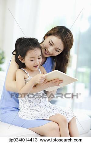 Stock Image - a mother and daughter reading a book together. Fotosearch