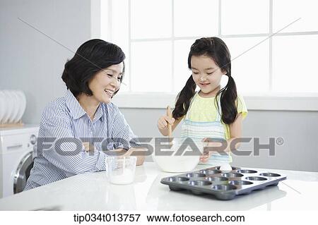 Stock Photo - a mother watching daughter cooking. Fotosearch