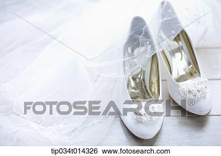 Stock Photograph - a pair of white heels with flower on the floor. Fotosearch