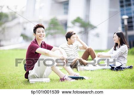 a student sitting on grass with students talking in background View Large Photo Image Stock Photo - a student sitting on grass with students talking in background. Fotosearch
