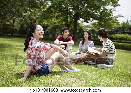 Stock Image - a student smiling at camera with friends studying in background. Fotosearch
