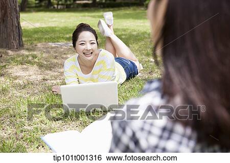 a university student lying on grass using laptop View Large Photo Image Stock Photograph - a university student lying on grass using laptop. Fotosearch