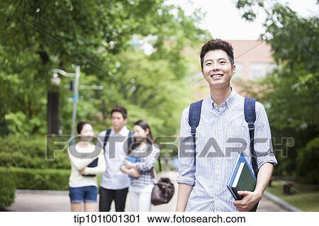 Stock Image - a university student standing in the campus smiling . Fotosearch