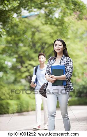 a university student walking in the campus holding books View Large Photo Image Stock Image - a university student walking in the campus holding books. Fotosearch