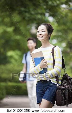 Stock Photo - a university student walking in the campus holding books. Fotosearch