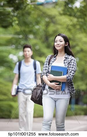 Stock Photography - a university student walking in the campus holding books. Fotosearch