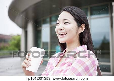 Stock Image - a university woman drinking coffee in the campus . Fotosearch