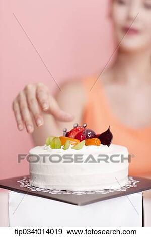 Stock Photo - a woman about to grab a cake in front of her. Fotosearch