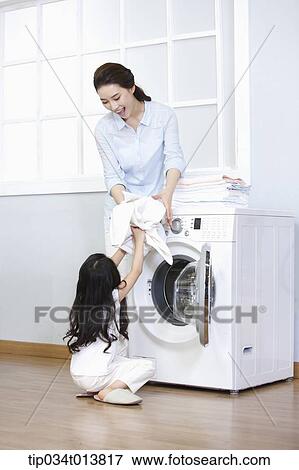Stock Photo - a woman and a daughter using washing machine . Fotosearch