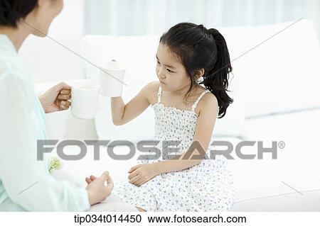 Stock Image - a woman and a girl drinking cup of tea . Fotosearch