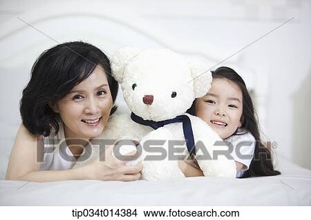 Picture - a woman and granddaughter lying on a bed. Fotosearch