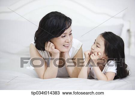 Stock Image - a woman and granddaughter lying on a bed. Fotosearch