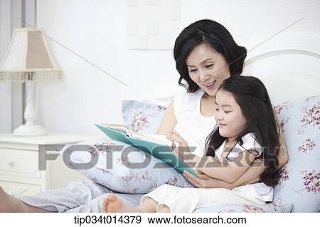 Stock Photo - a woman and granddaughter reading a book together. Fotosearch