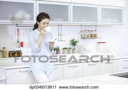 a woman drinking cup of coffee in the kitchen View Large Photo Image Stock Image - a woman drinking cup of coffee in the kitchen. Fotosearch