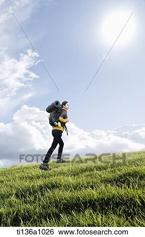 a woman hiking on a grass field View Large Photo Image Stock Photograph - a woman hiking on a grass field. Fotosearch
