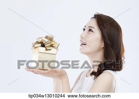 Picture - a woman in a white dress holding a present. Fotosearch