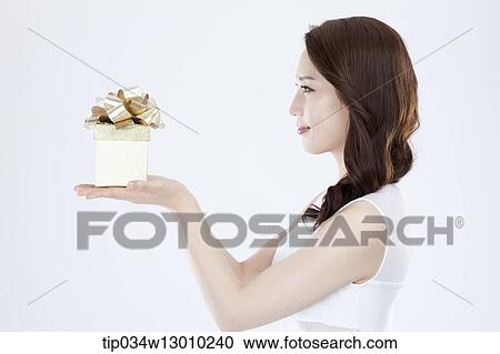 Stock Image - a woman in a white dress holding a present. Fotosearch