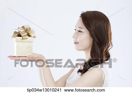 Stock Image - a woman in a white dress holding a present. Fotosearch