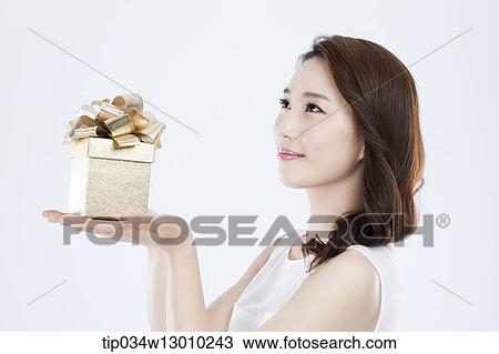 Stock Image - a woman in a white dress holding a present. Fotosearch