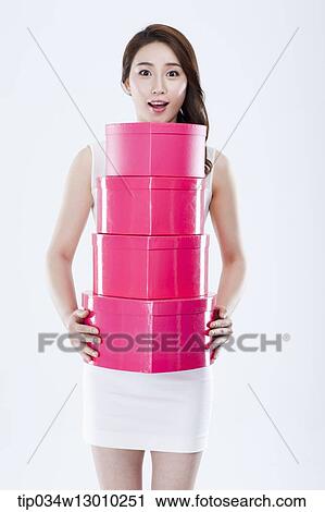 Stock Image - a woman in a white dress holding pink boxes. Fotosearch