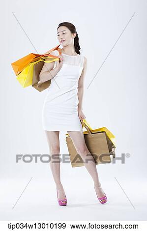 Stock Photo - a woman in a white dress holding shopping bags. Fotosearch