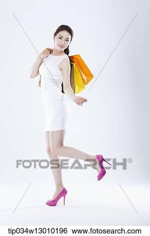 Stock Photograph - a woman in a white dress holding shopping bags. Fotosearch