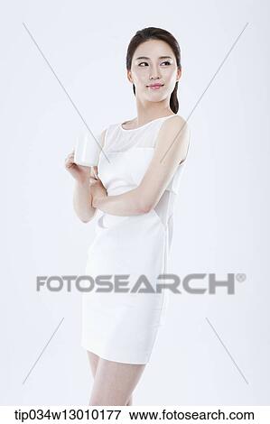 Stock Photo - a woman in a white dress posing with a glass of milk. Fotosearch