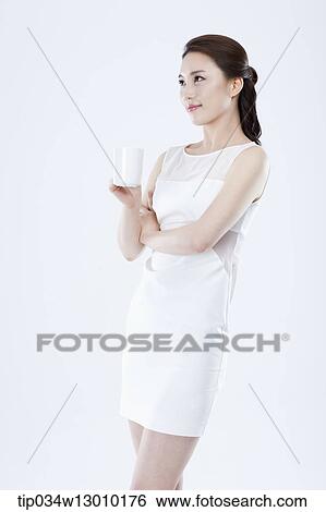 Stock Photograph - a woman in a white dress posing with a glass of milk. Fotosearch