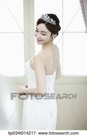 Stock Photo - a woman in wedding dress standing in front of window. Fotosearch