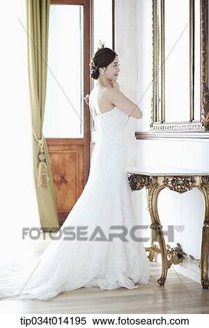 a woman in wedding dress standing in front of mirror View Large Photo Image Stock Photography - a woman in wedding dress standing in front of mirror . Fotosearch