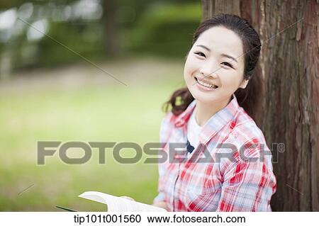a woman leaning on tree reading a book View Large Photo Image Stock Image - a woman leaning on tree reading a book. Fotosearch