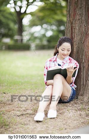a woman leaning on tree reading a book View Large Photo Image Stock Image - a woman leaning on tree reading a book. Fotosearch